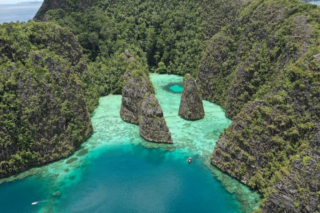 Stunning aerial shot of a tropical lagoon in Raja Ampat, Indonesia, showcasing vibrant turquoise water and lush greenery.