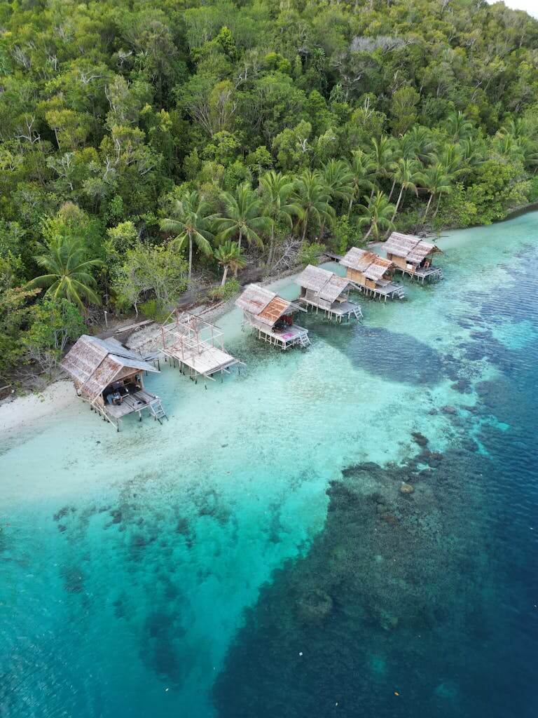 Stunning aerial shot of traditional huts along the tropical coast of Waigeo Barat, West Papua.