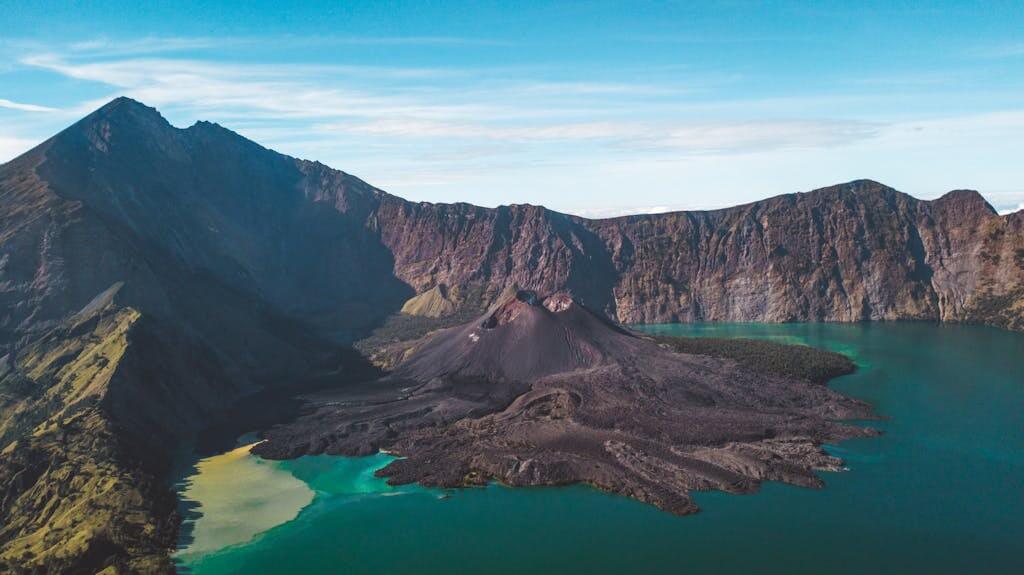 Stunning aerial view of a volcanic island surrounded by blue waters and rugged mountains.