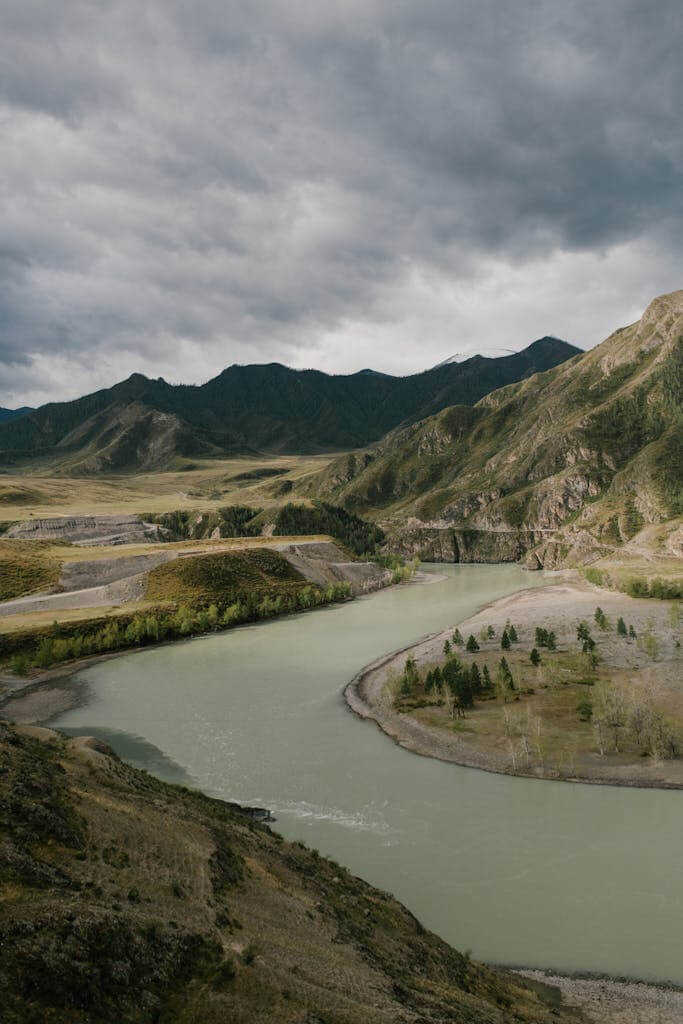Breathtaking view of a winding river through Mongolian mountains under a cloudy sky.